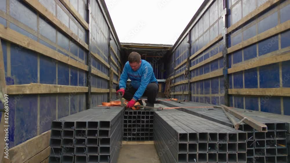 The man secures the metal in trailer The man secures the metal in trailer