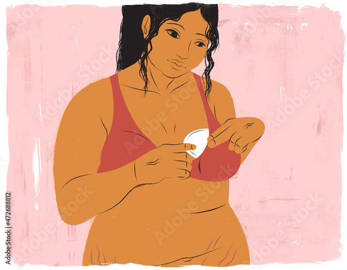 Breastfeeding mother inserting a lactation pad in bra