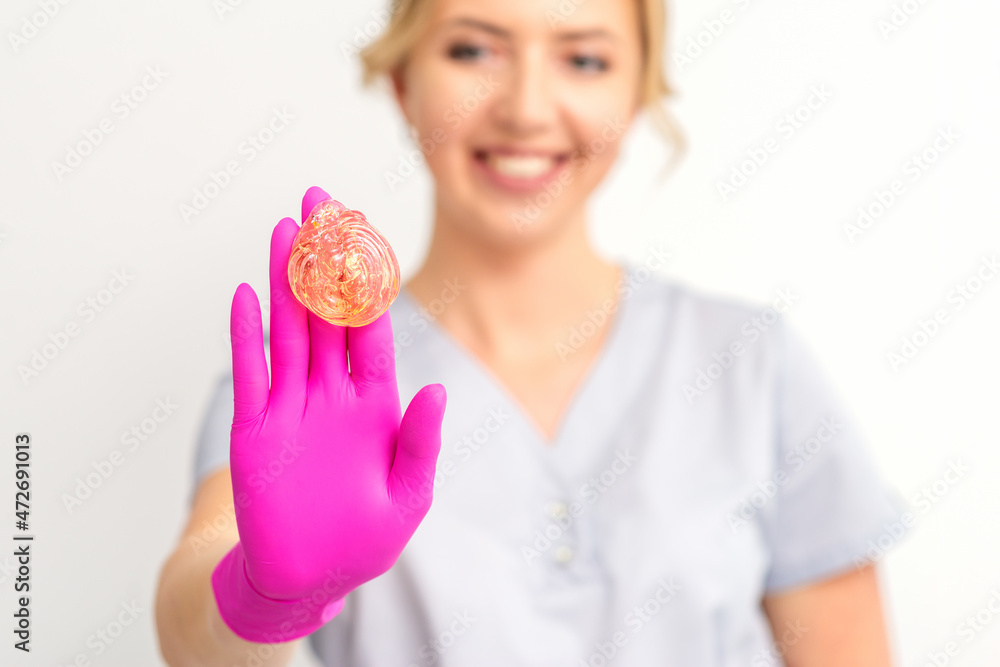 Yellow sugar paste in hand master of depilation. Smiling beautician holding wax for depilation over white background. Concept epilation Yellow sugar paste in hand master of depilation. Smiling beautician holding wax for depilation over white background. Concept epilation