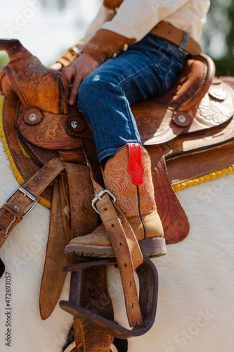 Person riding a horse with a cowboy boot in the stirrups of the saddle