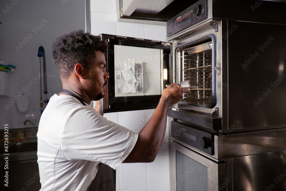 Black man putting fish in combi oven Black man putting fish in combi oven