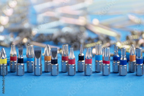 Screwdriver bits and fasteners of various kinds on a blue background. Copy space.