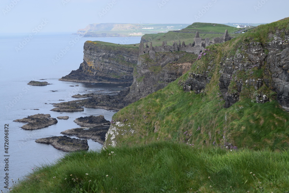 Green cliffs in Northern Ireland with ruins of a castle in the distance