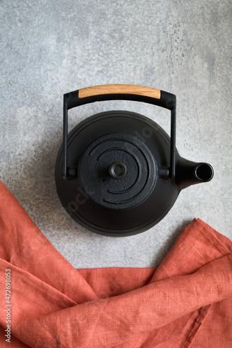 Asian black cast iron teapot and napkin on gray concrete background, top view, shallow depth of field