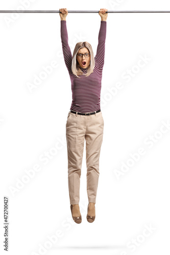 Scared young woman hanging and holding onto a bar photo