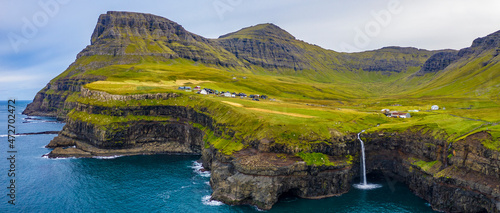 Fototapeta Naklejka Na Ścianę i Meble -  Europe, Faroe Islands. Aerial view of the village of Gasadalur and Mulafossur waterfall on the island of Vagar.