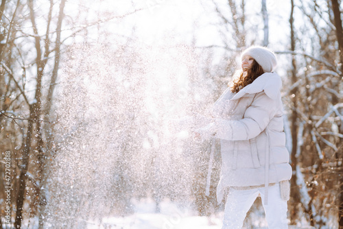 Happy woman in winter style clothes walking in the snowy park. Nature, holidays, rest, travel concept.