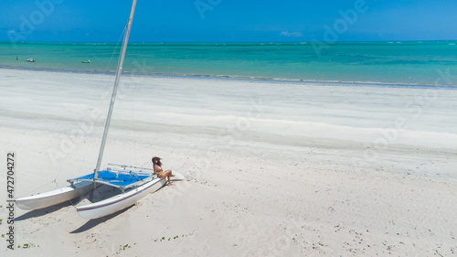 garota caminhando na praia com  águas verdes