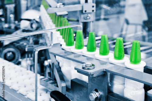 Close-up Many white plastic spray bottles for packaging liquid medicines or cosmetics in a row on a conveyor belt in a pharmaceutical manufacturing factory photo