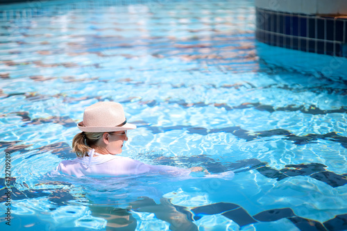 a woman wearing glasses and a white hat is in a beautiful blue pool