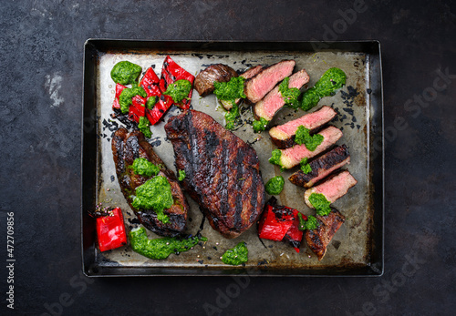 Traditional barbecue dry aged wagyu Brazilian picanha beef steaks served with chili and chimichurri sauce as top view on a rustic tray