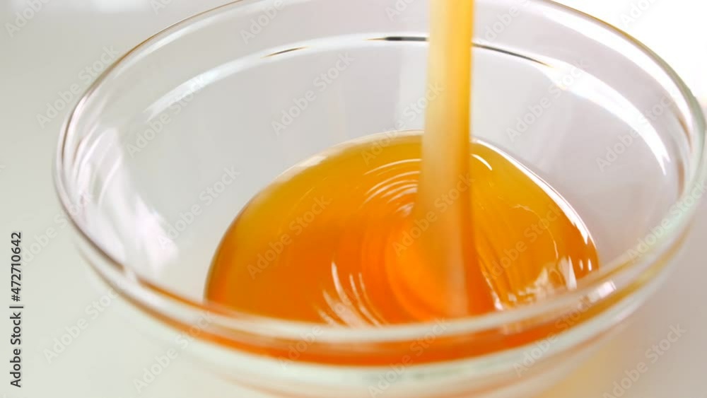 Fresh honey. Liquid honey in a transparent glass jar on a white background.Texture of honey close-up.slow motion. 4k footage Fresh honey. Liquid honey in a transparent glass jar on a white background.Texture of honey close-up.slow motion. 4k footage