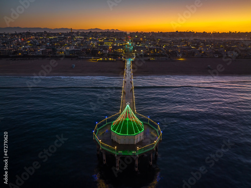 Manhattan Beach Pier with Christmas lights in California. Aerial View from end of Pier at Dawn with city and mountains in background.
