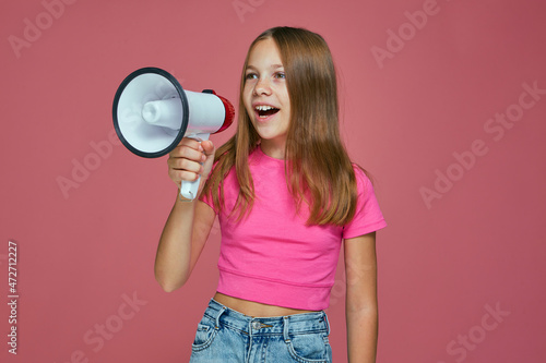 Happy cute little girl scream in megaphone news about sale discount on pink studio background. Baby store advertising