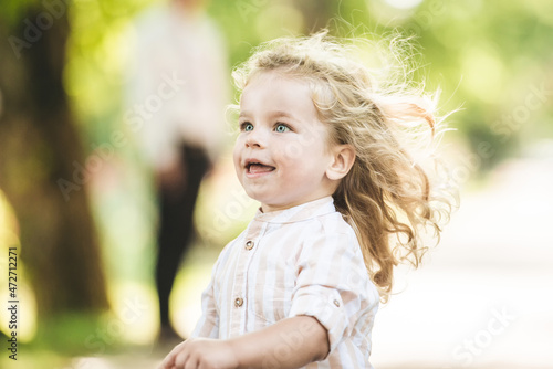 Cute little boy with curly blonde hair playing in park