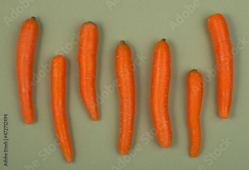 Top view of fresh carrots on green background. Flat lay.