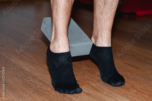 Men's feet in socks hold a brick for Pilates