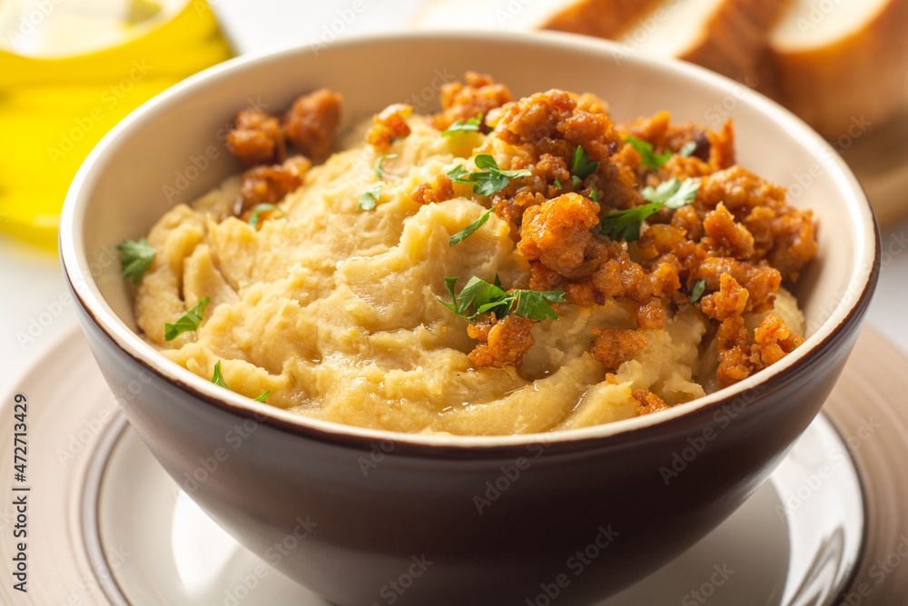 Yellow pea puree or porridge or pudding with meat sauce in bowl on concrete background Yellow pea puree or porridge or pudding with meat sauce in bowl on concrete background