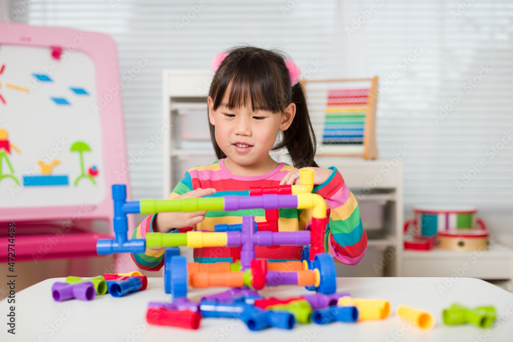 Fototapeta premium young girl playing water pipe construsction toy at home