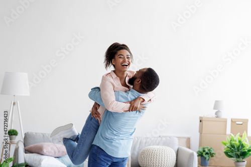 Fényképezés Happy couple moving at bought house, husband lifts up beloved wife, family begin