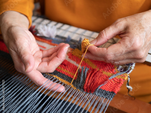 Master weaver is weaving the tapestry with diverse bright threads, close up. Artisanal at work