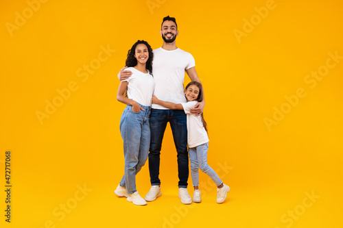 Middle-Eastern Parents And Daughter Embracing Expressing Positive Emotions, Yellow Background © Prostock-studio