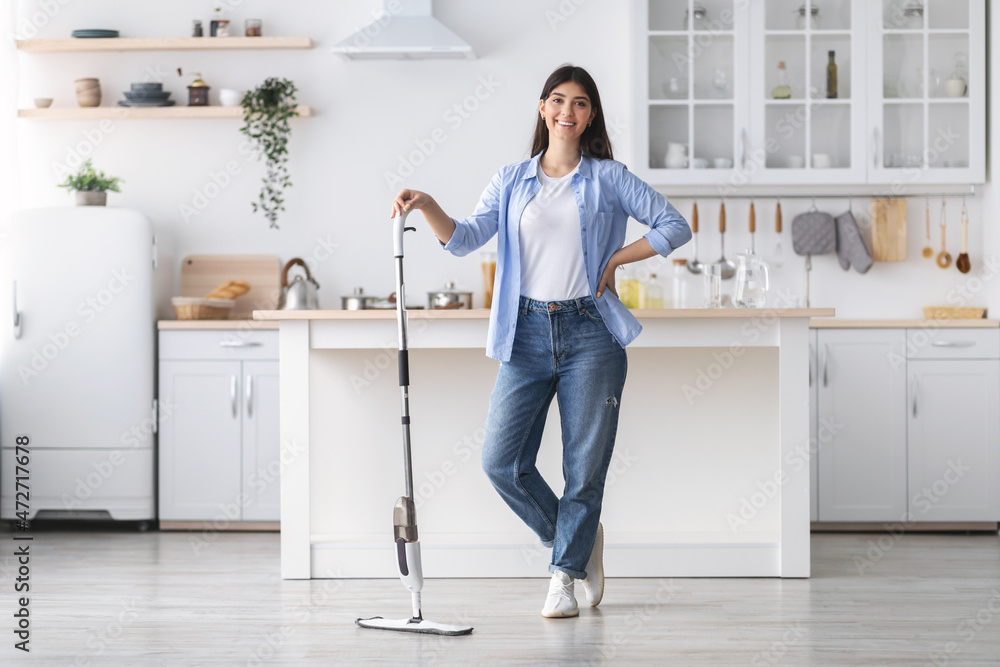 Portrait of cheerful woman cleaning floor with spray mop, posing Portrait of cheerful woman cleaning floor with spray mop, posing