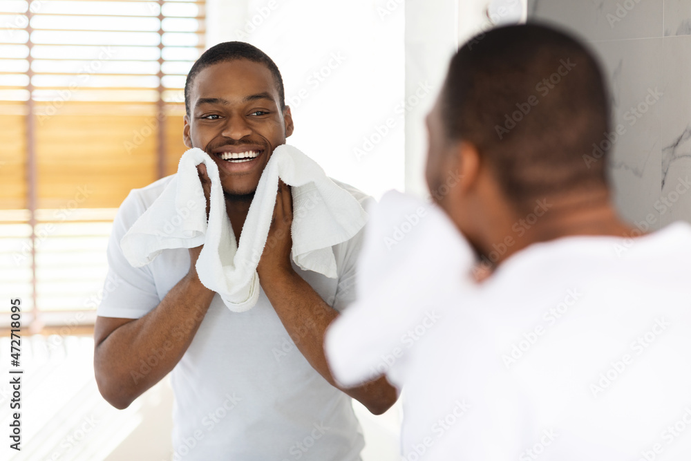 Aftershave Care Concept. Handsome Black Guy Wiping Face With Towel In Bathroom Aftershave Care Concept. Handsome Black Guy Wiping Face With Towel In Bathroom