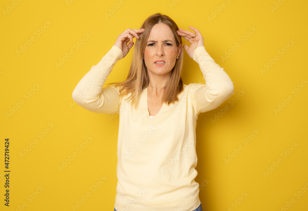 Young beautiful woman wearing casual sweater over yellow isolated background suffering from headache desperate and stressed because pain and migraine. Hands on head. Young beautiful woman wearing casual sweater over yellow isolated background suffering from headache desperate and stressed because pain and migraine. Hands on head.