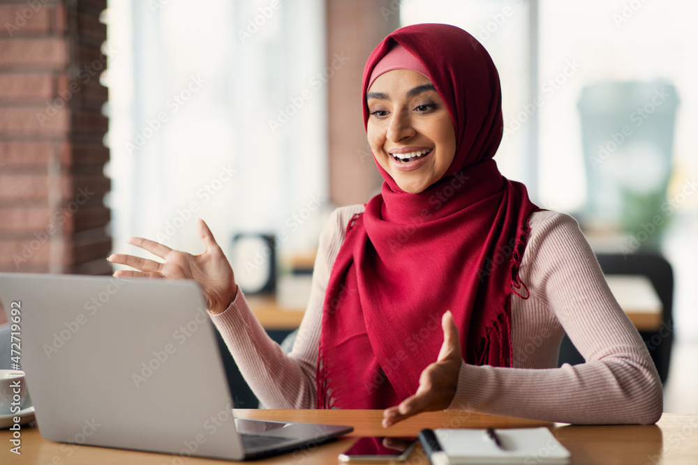 Emotional muslim woman having online job interview, using laptop