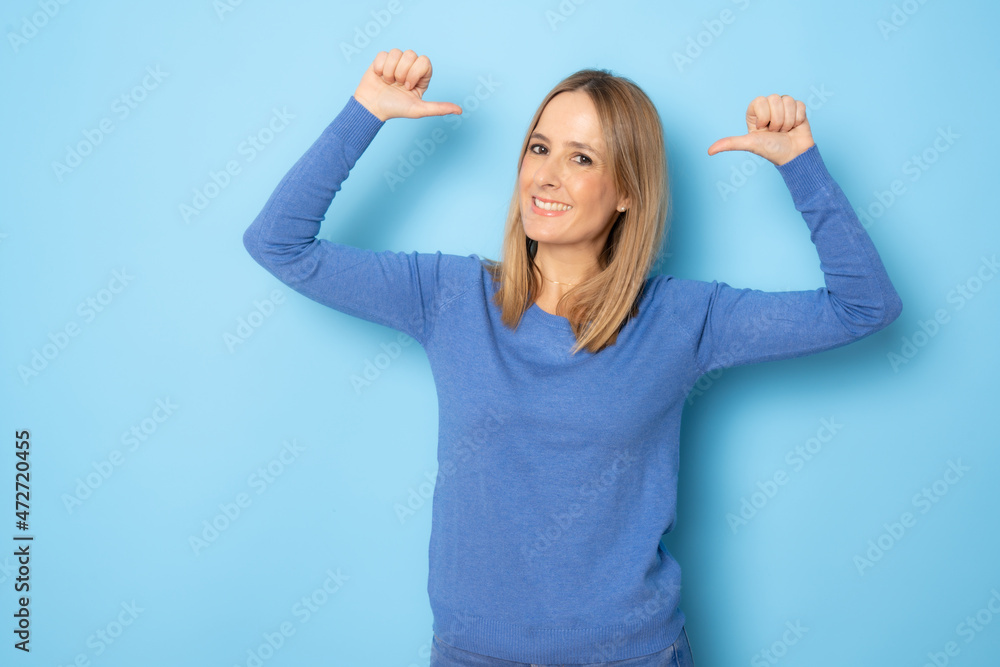 Young smiling woman in casual sweater showing with thumbs up isolated over blue background. Young smiling woman in casual sweater showing with thumbs up isolated over blue background.