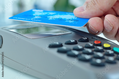 Hand using blue credit card for payment with nfc techology.