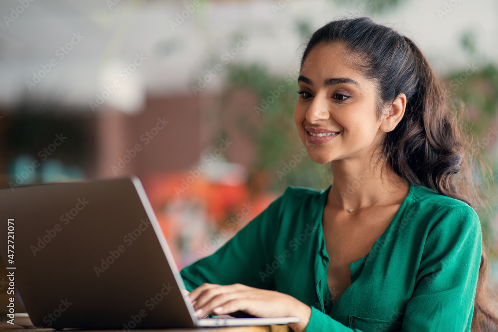 Indian woman studying online at cafe, using laptop, empty space Indian woman studying online at cafe, using laptop, empty space