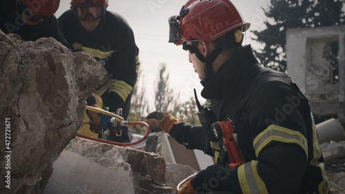 Obraz na plátne Man in protective hardhat and uniform talking with coworkers while searching for