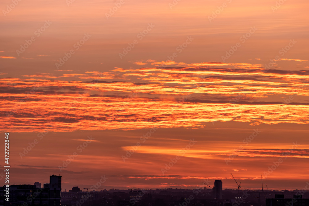 A orange colored sunset sky above a city skyline as texture or background