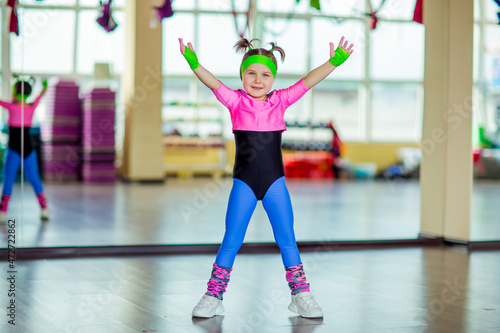 a small  beautiful girl doing sports in the gym in bright  colored sportswear