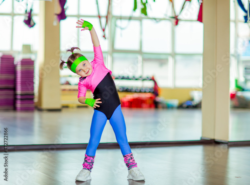 a small, beautiful girl,doing sports in the gym,in bright, colored sportswear