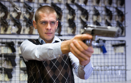 Man takes aim with a revolver when choosing in a gun store