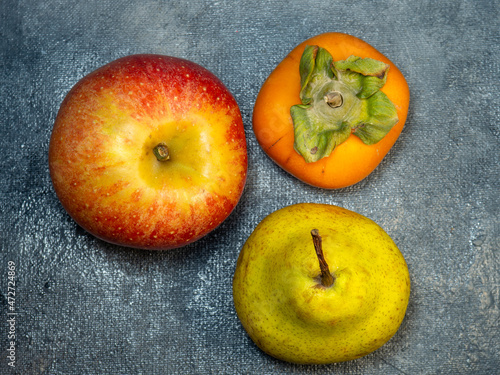 apple, persimmon and pear on a black background. Persimmon Chamomile. Apple Gala. Pear lucas. Still life of fruits