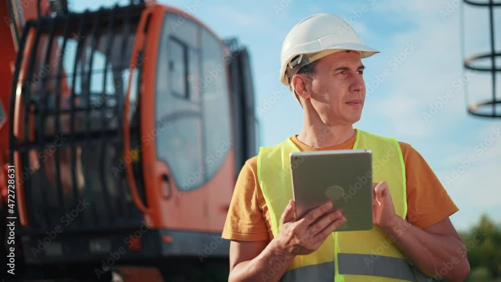 worker in hard a hat with digital tablet near excavator. construction site driver with online digital tablet. industry construction business concept. worker hard hat near excavator truck in uniform. worker in hard a hat with digital tablet near excavator. construction site driver with online digital tablet. industry construction business concept. worker hard hat near excavator truck in uniform.