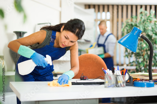 Close-up of asian female worker cleaning white desk in modern office using disinfectant