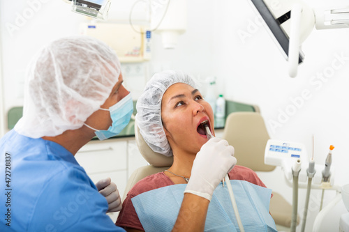 Dentist checks the patient teeth using special instrument and a computer