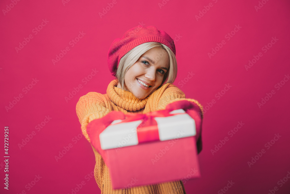 Caucasian woman reaching out decorated gift box to the camera isolated over pink background. Smiling face looking to the camera. Happy new year. Christmas Caucasian woman reaching out decorated gift box to the camera isolated over pink background. Smiling face looking to the camera. Happy new year. Christmas