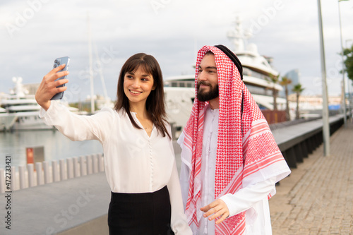 Diverse business partners caucasian woman and arab man taking selfie in port after successful deal © Igor Kardasov