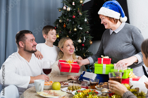 Happy family celebrating Christmas together at home, cheerful senior woman presenting gifts .