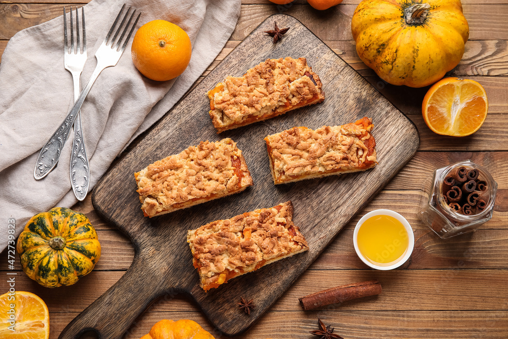 Board with pieces of tasty pumpkin pie on wooden background Board with pieces of tasty pumpkin pie on wooden background