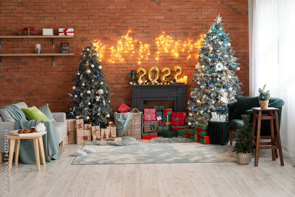 Obraz premium Interior of festive living room with Christmas trees, decorative mantelpiece and sofas