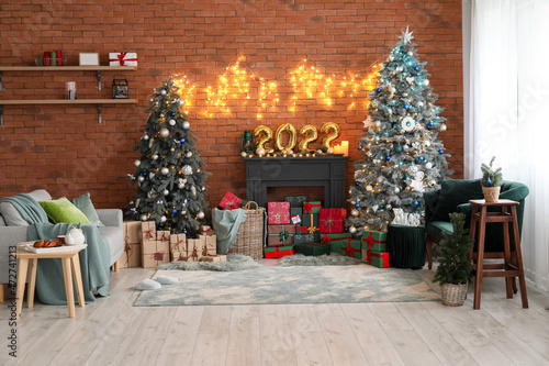 Interior of festive living room with Christmas trees, decorative mantelpiece and sofas © Pixel-Shot