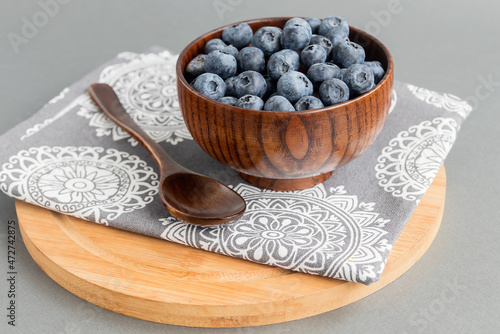 Ripe healthy tasty blueberries in a small wooden bowl. 