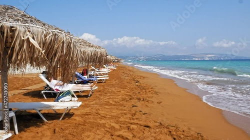 Tourists Relaxing On Sunbeds On A Sandy Beach Of Megas Lakkos In Greece - static shot photo